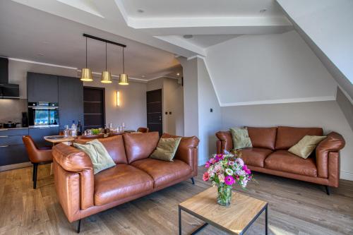a living room with brown leather couches and a table at La Perle de Domme in Sarlat-la-Canéda