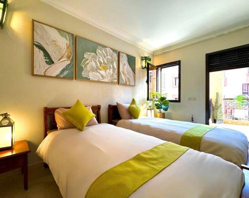 two beds in a room with paintings on the wall at Piscine Guéliz Center Yoga in Marrakech