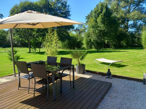a wooden deck with a table and an umbrella at L'Oasis Des Pyrénées in Campuzan
