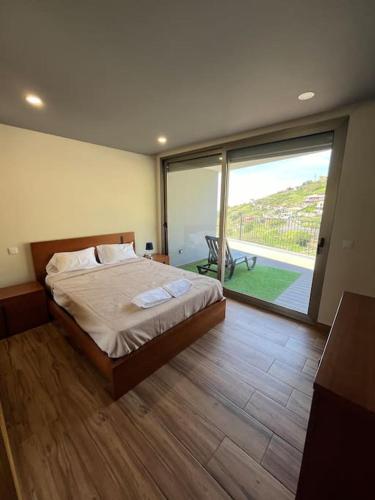 a bedroom with a bed and a large window at Sunset Valley House in Ribeira Brava