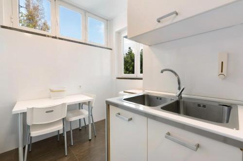 a white kitchen with a sink and a table at Spacious Apartment T3 Near Beach in Estoril