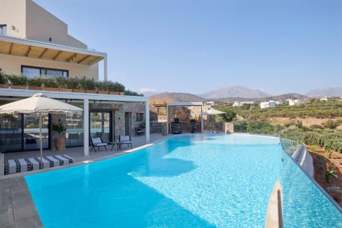 a swimming pool in a villa with mountains in the background at Mirabello Bay Luxury Resort in Agios Nikolaos