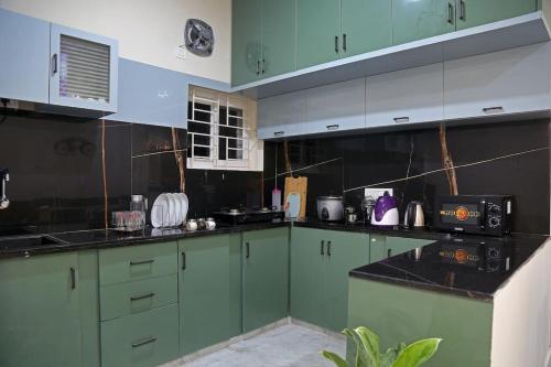 a kitchen with green cabinets and black counter tops at Aavasam - 3BHK- Gachibowli in Hyderabad