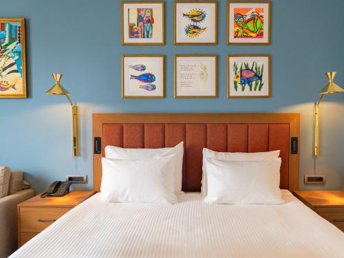 a bedroom with a bed with white pillows and framed pictures at Sundia Exclusive By Liberty Fethiye Adults Only in Fethiye