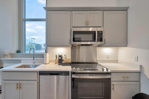 a kitchen with white cabinets and a sink and a microwave at Bright and Modern Studio in Louisville # 301 in Louisville