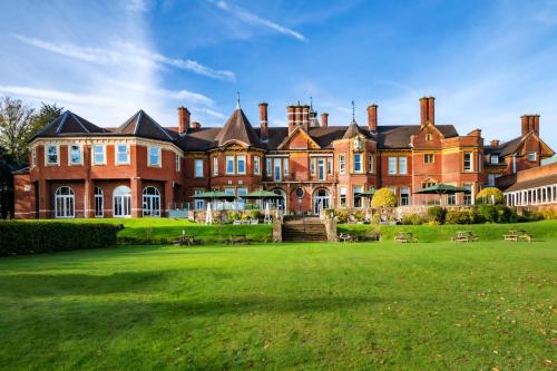 a large brick building with a green lawn in front at Moor Hall Hotel & Spa in Sutton Coldfield