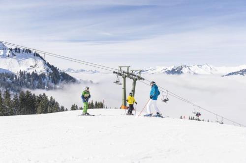 three people on a ski lift on a ski slope at Berghaus Lutzklang in Raggal