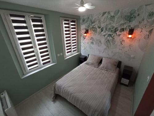 a bedroom with a bed and two windows at Le Rêve Bulle in Abbeville