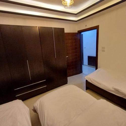 a bedroom with two beds and a cabinet and a window at Laperla luxury family apartment one in Amman