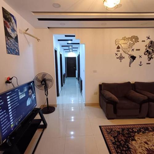 a living room with a couch and a flat screen tv at Laperla luxury family apartment one in Amman