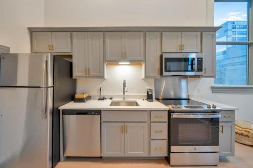 a kitchen with white cabinets and a stainless steel refrigerator at Bright and Modern Studio in Louisville # 302 in Louisville