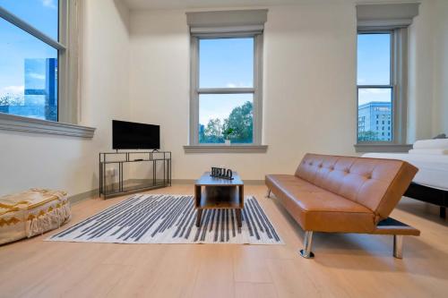 a living room with a brown leather couch and a bed at Bright and Modern Studio in Louisville # 302 in Louisville