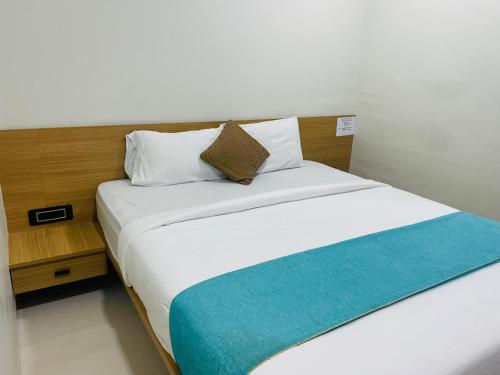 a bedroom with a large white bed with a wooden headboard at Hotel Sai Palace Inn in Puttaparthi