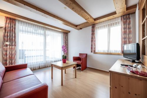 a living room with a couch and a tv at Hotel Vorab - Familienbetrieb mit Herz in Flims