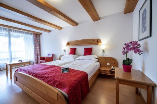 a bedroom with a large bed with red pillows at Hotel Vorab - Familienbetrieb mit Herz in Flims