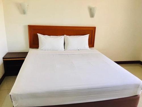 a large bed with white sheets and pillows at KP Hotel Udonthani in Amphoe Kumphawapi