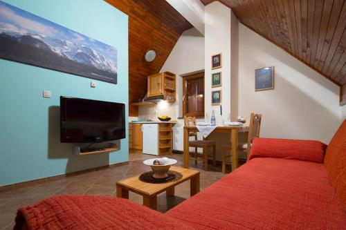 Una sala de estar con un sofá rojo y una cocina. en Apartments Aurora, en Risovac