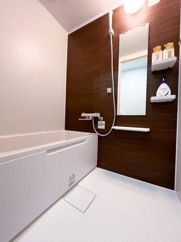 a bathroom with a bath tub and a mirror at Ikebukuro Area 1F03 NishiikeApartment in Tokyo