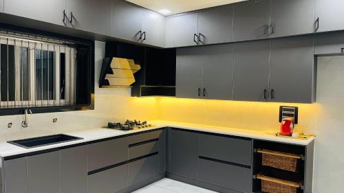 a kitchen with gray and yellow cabinets and a sink at Hotel Sai Palace Inn in Puttaparthi