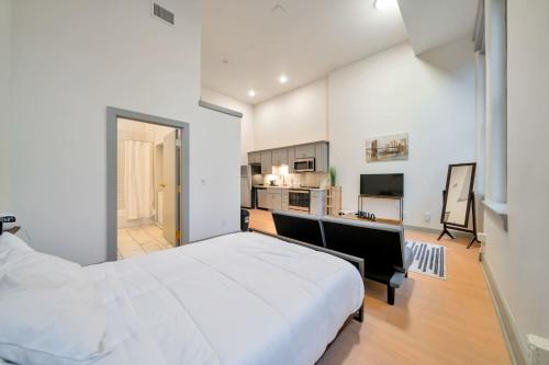 Un dormitorio con una gran cama blanca y una cocina. en Bright and Modern Studio in Louisville # 306, en Louisville