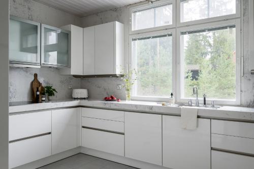 a white kitchen with white cabinets and a window at Villa Lago, Tahko in Tahkovuori