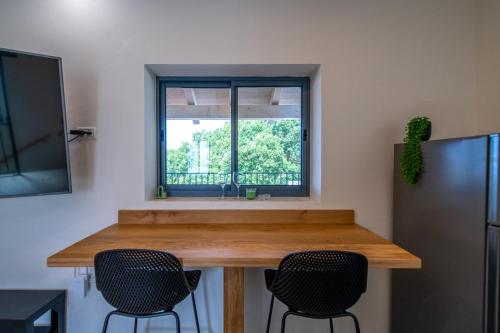 a kitchen with a table with chairs and a window at חדרי אירוח בהט in Ein Zivan