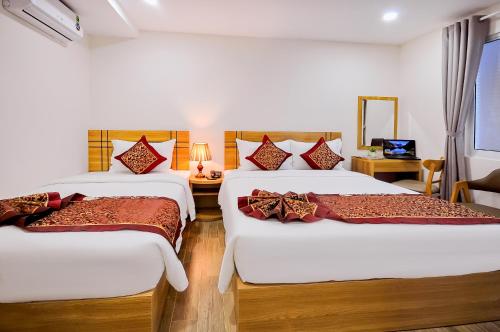 a hotel room with two beds and a desk at May Ngu Sac - Iridescent Clouds Hotel in Nha Trang