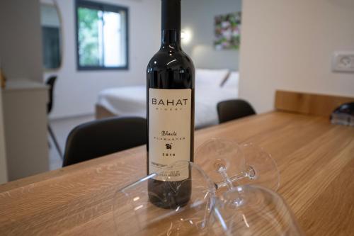 a bottle of wine sitting on top of a wooden table at חדרי אירוח בהט in Ein Zivan