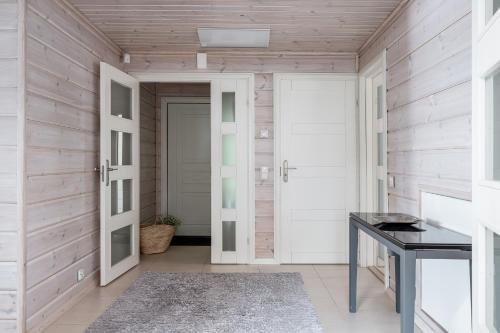 a hallway with white doors and a table at Villa Lago, Tahko in Tahkovuori