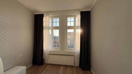 an empty room with a window with black curtains at Diamond Apartment in Grudziądz