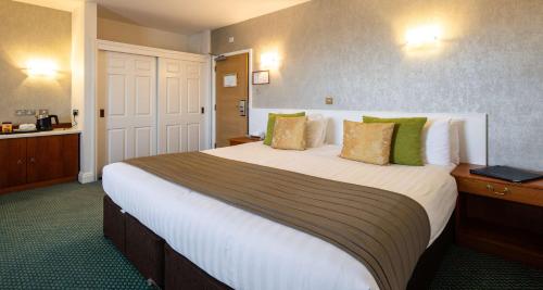 a hotel room with a large bed with green pillows at The Monterey Hotel - Sure Hotel Collection by Best Western in Saint Helier Jersey