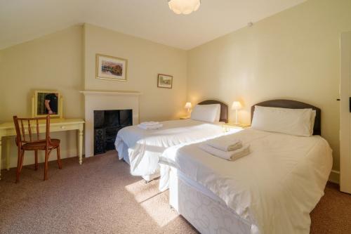 a bedroom with two beds and a desk and a fireplace at 7 Low Glenridding - with private parking in Glenridding