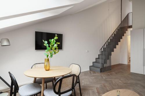 a dining room with a table and chairs and a staircase at Limehome Prague Halkova in Prague