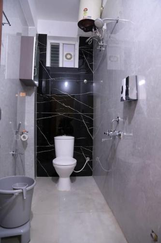 a bathroom with a toilet and a black tiled wall at Aavasam - 3BHK- Gachibowli in Hyderabad