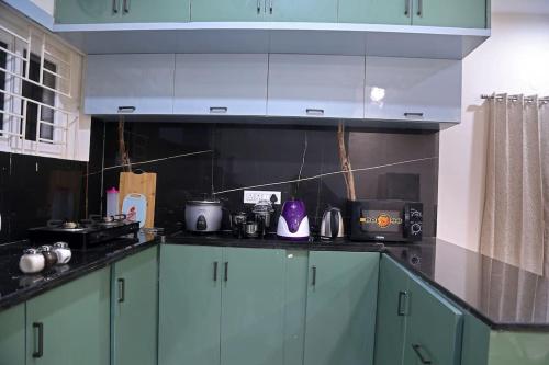 a kitchen with green cabinets and black counter tops at Aavasam - 3BHK- Gachibowli in Hyderabad