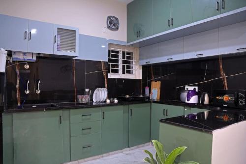a kitchen with green cabinets and black counter tops at Aavasam - 3BHK- Gachibowli in Hyderabad