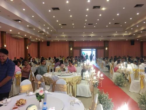 a group of people sitting at tables in a banquet hall at KP Hotel Udonthani in Amphoe Kumphawapi