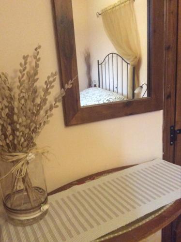 a mirror and a vase with flowers on a table at Ey-Giann in Karpenision