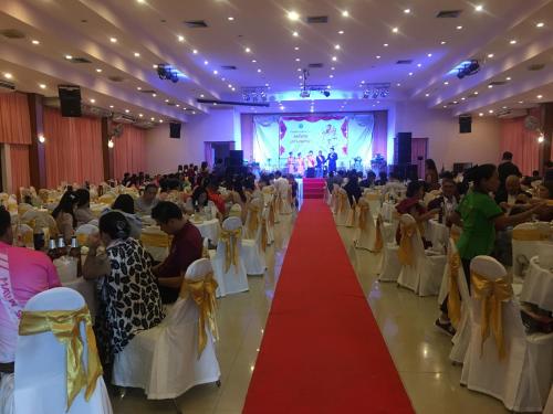 a crowd of people sitting in a banquet hall with a red carpet at KP Hotel Udonthani in Amphoe Kumphawapi