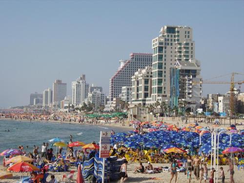 a crowd of people on a beach with umbrellas at Ben Yehuda Apartments in Tel Aviv