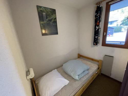 un petit lit dans une chambre avec une fenêtre dans l'établissement Charmant T2 cabine au pied des pistes avec balcon et commodités - FR-1-787-85, à Laveissière