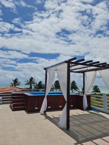 acovered deck with a canopy and a swimming pool at Hotel Paraiso Maragogi LTDA in Maragogi