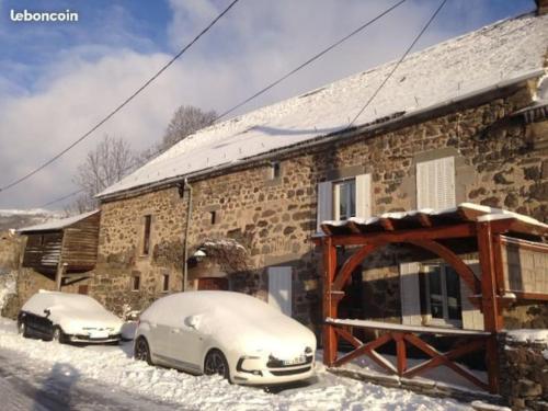 two cars parked outside of a building in the snow at Maison proximité station de ski le lioran in Laveissière