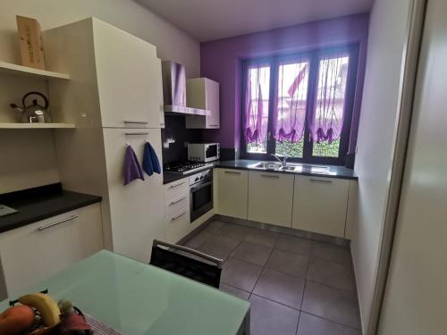 a kitchen with purple walls and white cabinets at Casa Violetta in Alba