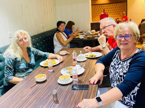 a group of people sitting at a table eating food at HotelMaple Ridge in Tājganj