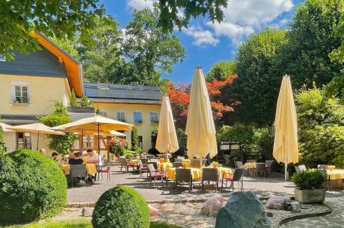 a patio with tables and umbrellas in front of a building at Hotel Restaurant Rengser Mühle in Bergneustadt