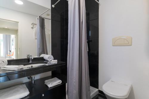 een badkamer met een wastafel, een toilet en een spiegel bij Villa Nogueira V with Private Pool by Holiday Rental Madeira in Funchal