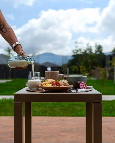 a person is pouring milk into a table with a plate of food at Batalha Golf Villas & Spa in Ponta Delgada