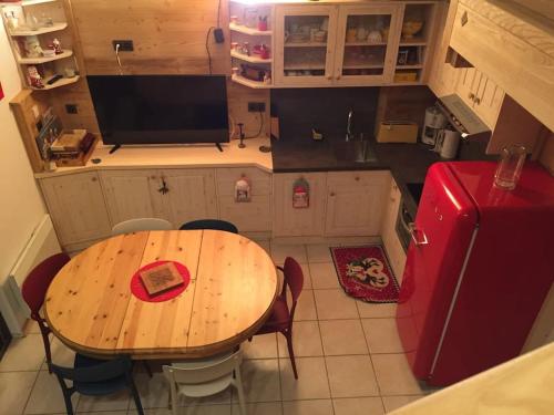 Il comprend une cuisine équipée d'une table en bois et d'un réfrigérateur rouge. dans l'établissement Apartment Manigod-L'Étale-La Clusaz skIs aux pieds, à Manigod