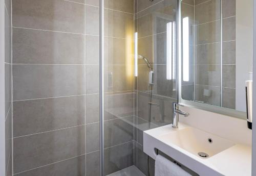 ein Badezimmer mit Dusche, Waschbecken und Spiegel in der Unterkunft B&B HOTEL Bordeaux Saint André de Cubzac in Saint-André-de-Cubzac